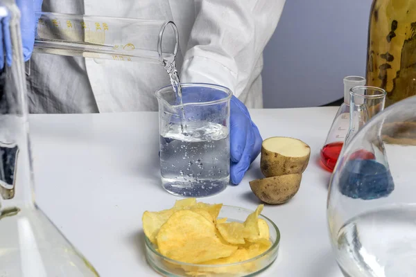 Experto en seguridad alimentaria sosteniendo tubos de ensayo en las manos revisando papas fritas en el laboratorio — Foto de Stock