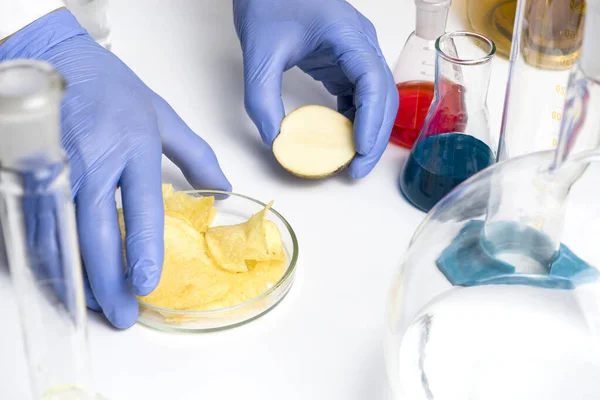 Assistente di laboratorio sul posto di lavoro vista dall'alto. Procedura di laboratorio per la sicurezza alimentare, analisi degli alimenti dal mercato. Nelle patatine ci sono segni con il codice E-integratori . — Foto Stock