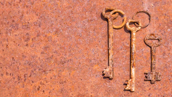 3 viejas llaves oxidadas en el anillo disparado sobre fondo texturizado de acero. Copiar espacio . — Foto de Stock