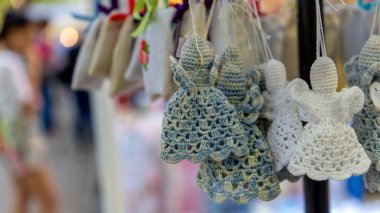 İplere asılmış melek şeklinde el yapımı oyuncaklar. Bulanık arkaplan.