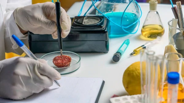 Photo laboratory assistant at the workplace makes notes in a notebook. Laboratory procedure for food safety, analysis of food products from the market.