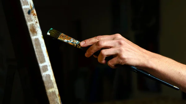 Side view of someone painting some picture with a brush isolated on black background — Stock Photo, Image