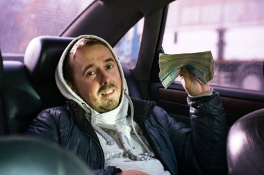 Para büyük bir bohça ile bir arabada oturan bir genç adam.