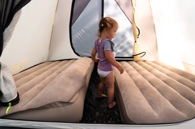 Kamp alanında, küçük bir kız bir çadır minder üzerinde atlar..