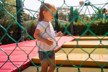 koruyucu bir ağ arkasında bir trambolin üzerinde atlama kız