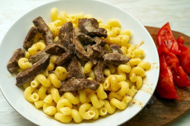 Beyaz tabakta sığır ciğeri ve makarna.