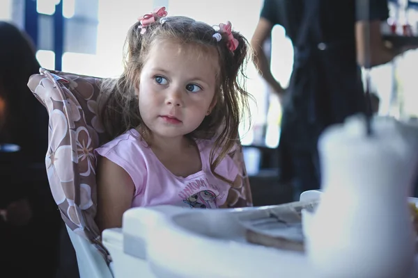 Restoranda bebek sandalyesinde oturan küçük kız.