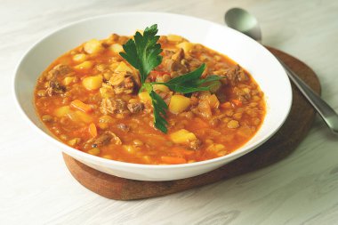 Tahtada beyaz bir tabakta mercimek çorbası
