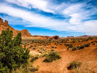 Geniş gökyüzü ve bulutların altında çorak arazisi olan çöl manzarası, Arches National Park, UT, ABD