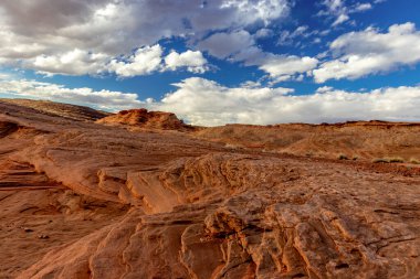 Mavi gökyüzü, yuvarlanan bulutlar ve kayanın kumtaşı katmanları, The Chains, Page, Arizona, ABD