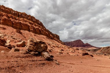 Zaman içinde dağların etrafına dağılmış çeşitli büyüklükteki kayalar, Vermillion yamaç sırası, Page, AZ, ABD