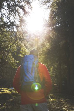 adam mavi sırt çantası ve ormanın içinde kırmızı kazaklı hiking