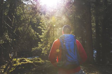 adam mavi sırt çantası ve ormanın içinde kırmızı kazaklı hiking