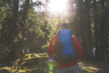 adam mavi sırt çantası ve ormanın içinde kırmızı kazaklı hiking