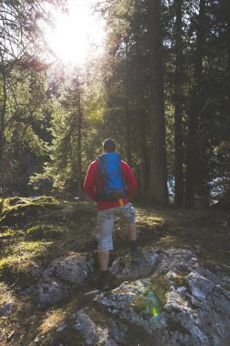 adam mavi sırt çantası ve ormanın içinde kırmızı kazaklı hiking