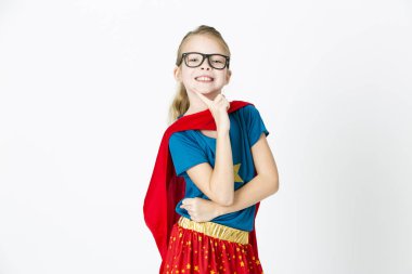 blond supergirl with glasses and red robe und blue shirt is posing in the studio clipart
