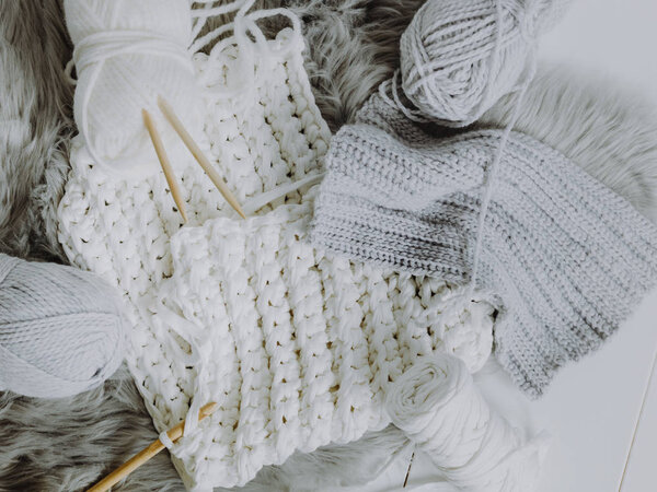 White and gray wool with crochet hook and knitting needles