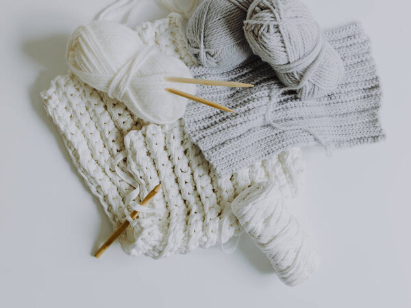 Близкий вид на белую и серую шерсть с крючком и вязальными спицами
