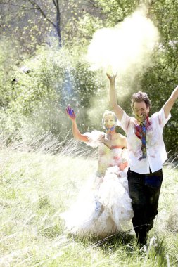 Genç ve güzel gelin ve damat renkli holi tozuyla birlikte vakit geçiriyorlar.