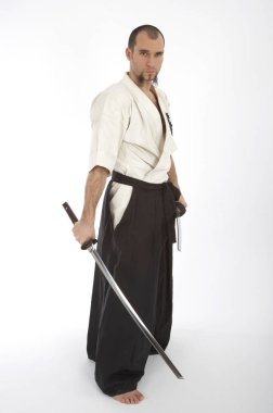 Kimono eğitimi almış ciddi bir erkek karate dövüşçüsü beyaz stüdyo arka planında izole edilmiş, dövüş sanatları konsepti. 