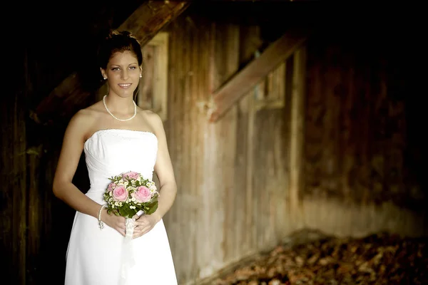 漂亮的年轻新娘穿着白色婚纱在木制谷仓里的特写镜头 — 图库照片
