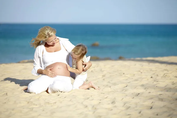 Jovem Mulher Grávida Abraçando Filha Enquanto Sentado Praia Areia — Fotografia de Stock