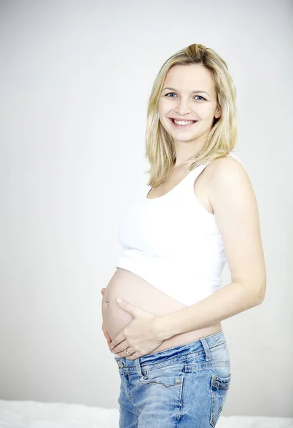 Leende Gravid Kvinna Kupade Magen Båda Händerna Och Tittar Kameran — Stockfoto