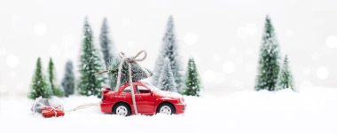Minyatür kırmızı arabasıyla Karlı Kış Ormanı Noel ağacı ve hediyeler taşıyor.