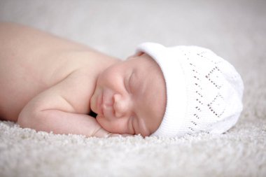 3 hafta yeni doğan bebek yorgan üzerinde uyku beyaz şapkalı 
