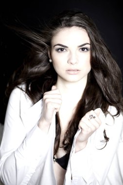 Kameraya bakarak ve koyu arka plan üzerinde poz güzel siyah saçlı genç kadın model giyen beyaz portre gömlek 