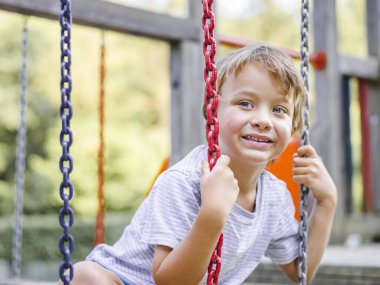 Sarışın çocuk oyun alanında maymun salıncak oynarken eğleniyor 