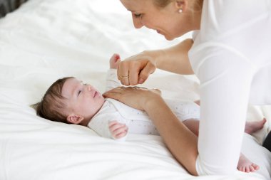 Genç anne yatakta masaj şirin bebek