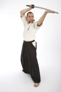 Kimono eğitimi almış ciddi bir erkek karate dövüşçüsü beyaz stüdyo arka planında izole edilmiş, dövüş sanatları konsepti. 
