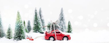 Minyatür kırmızı arabasıyla Karlı Kış Ormanı Noel ağacı ve hediyeler taşıyor.
