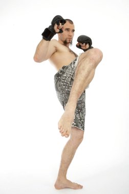 Beyaz stüdyo arka planında yalnız poz veren boks eldivenli kasvetli bir sporcu.