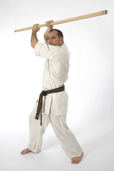 认真的男性空手道选手在和服训练中用木棍隔离在白色工作室背景下 武术概念 — 图库照片