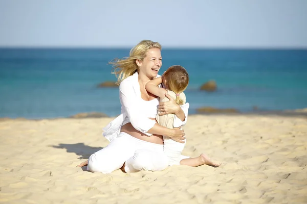 Giovane Donna Incinta Abbracciare Figlia Mentre Seduto Sulla Spiaggia Sabbia — Foto Stock