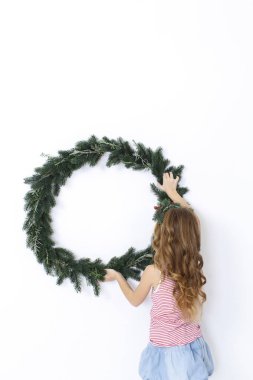 Beyaz arka plan üzerinde izole Noel çelenk ile poz mutlu güzel kız