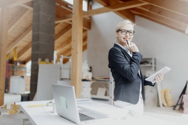 genç kadın mimar dizüstü bilgisayar ve planları loft adlı tablo yakın dururken Tablet PC'yi kullanma 