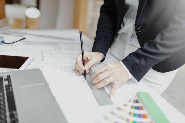 Şantiyedeki takım elbiseli çekici genç bayan mimar planlarla çalışıyor.