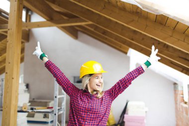 güvenlik kask mutlu sarışın güzel mimar kadın çatı kolları ile ayakta, fikir kavramı loft genişletmek için 