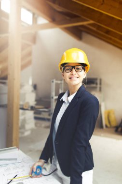 evde çatı çalışan sarı kask ve siyah ceket giyen güzel genç kadın mimar
