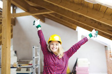 güvenlik kask mutlu sarışın güzel mimar kadın çatı kolları ile ayakta, fikir kavramı loft genişletmek için 