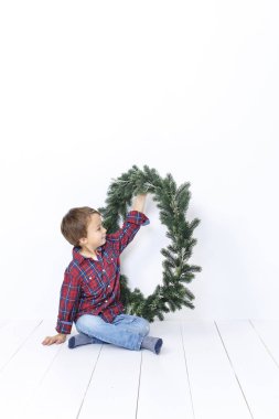 Beyaz arka plan üzerinde izole Noel çelenk ile poz mutlu küçük çocuk
