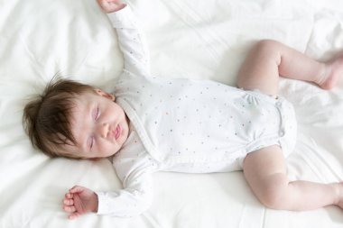 Noktalı vücutlu şirin bebek yatakta yatıyor.