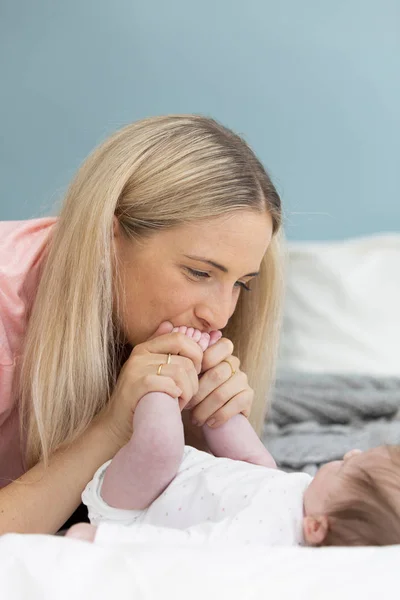 Genç Güzel Pembe Gömlekli Sarışın Anne Bebeğini Yatakta Kucaklıyor — Stok fotoğraf