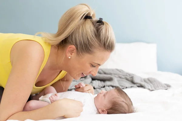 Όμορφη Νεαρή Μητέρα Κίτρινο Πουκάμισο Μωρό Της Στο Κρεβάτι Αγκαλιάζονται — Φωτογραφία Αρχείου