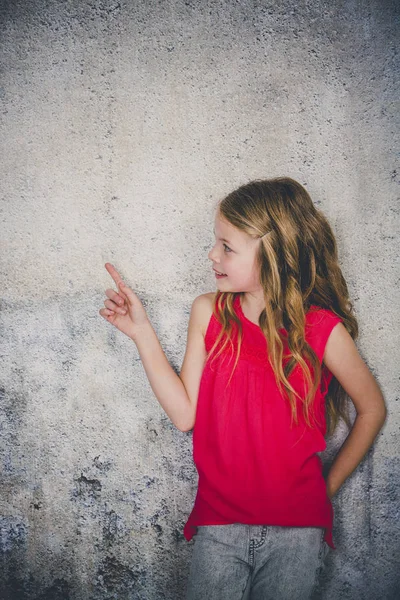 Beautiful Girl Red Shirt Pointing Aside While Standing Front Concrete Royalty Free Stock Photos