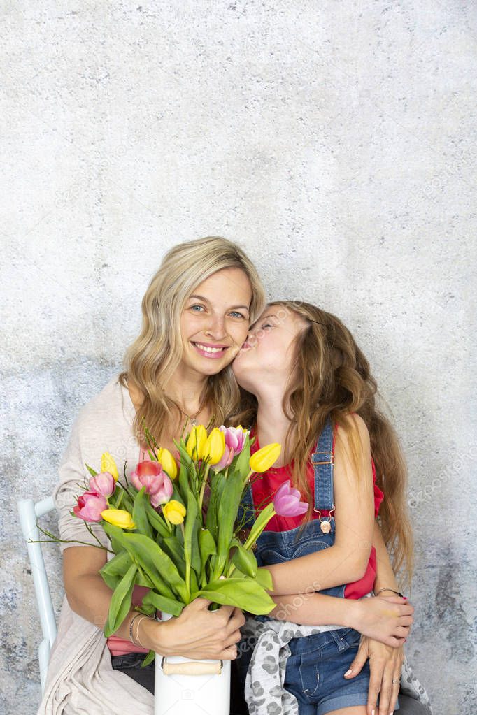 daughter kissing and congratulating mother with bouquet of colorful flowers, Mother day concept  