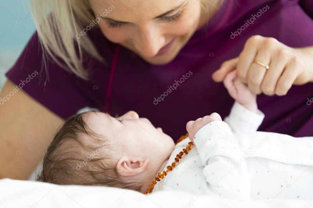 beautiful blond mother with her 3 month old baby wearing a amber necklace